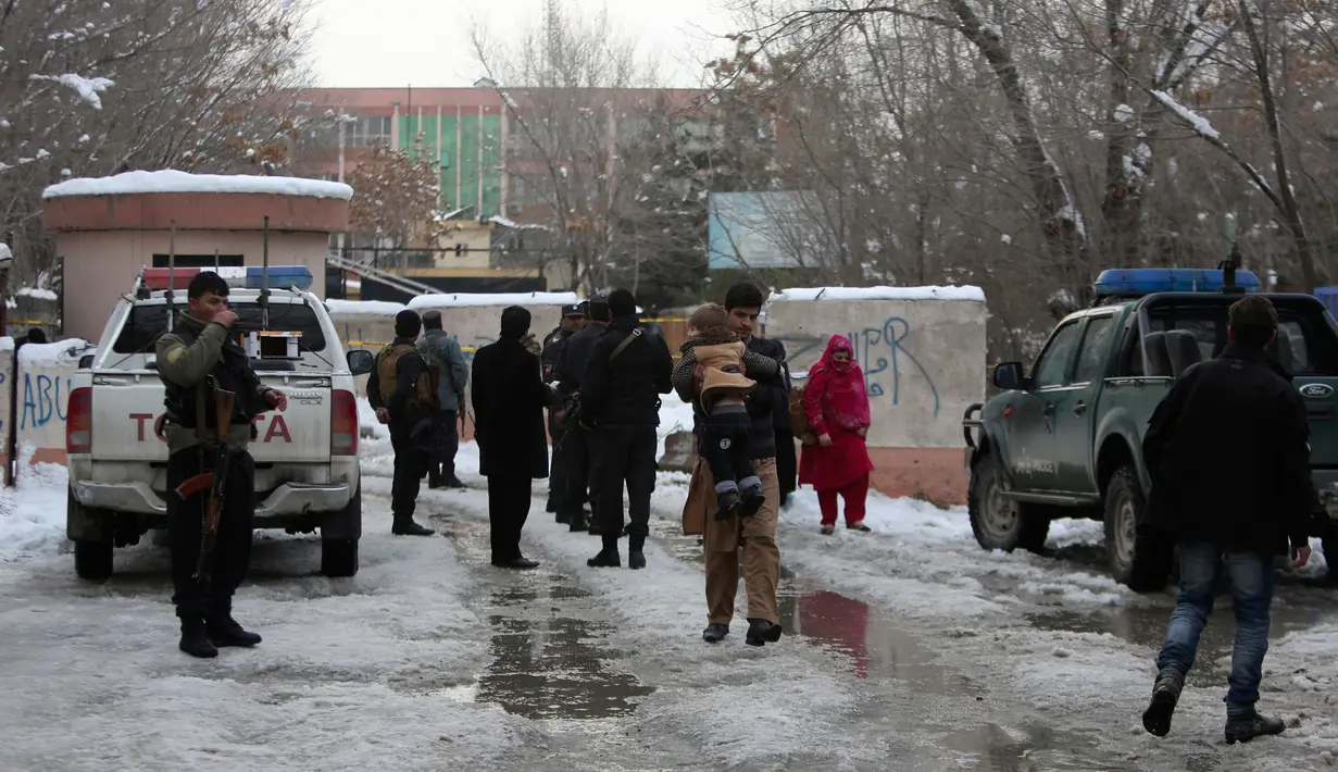 Seorang pria menggendong anak kecil melewati lokasi serangan bom yang terjadi di kompleks Mahkamah Agung (MA) di ibu kota Afghanistan, Kabul, Selasa (7/1). Setidaknya dilaporkan ada 20 orang yang tewas akibat ledakan itu. (AP Photo/Rahmat Gul)