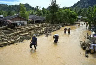 Hingga saat ini listrik masih padam di Tapanuli Tengah dan akses internet masih terbatas menggunakan Starlink, termasuk Bahan Bakar Minyak (BBM) hingga gas elpiji. Tampak dalam foto, warga berjalan di tengah banjir bandang di Desa Tukka, Tapanuli Tengah, Sumatera Utara, pada 2 Desember 2025. (YT HARIONO/AFP)