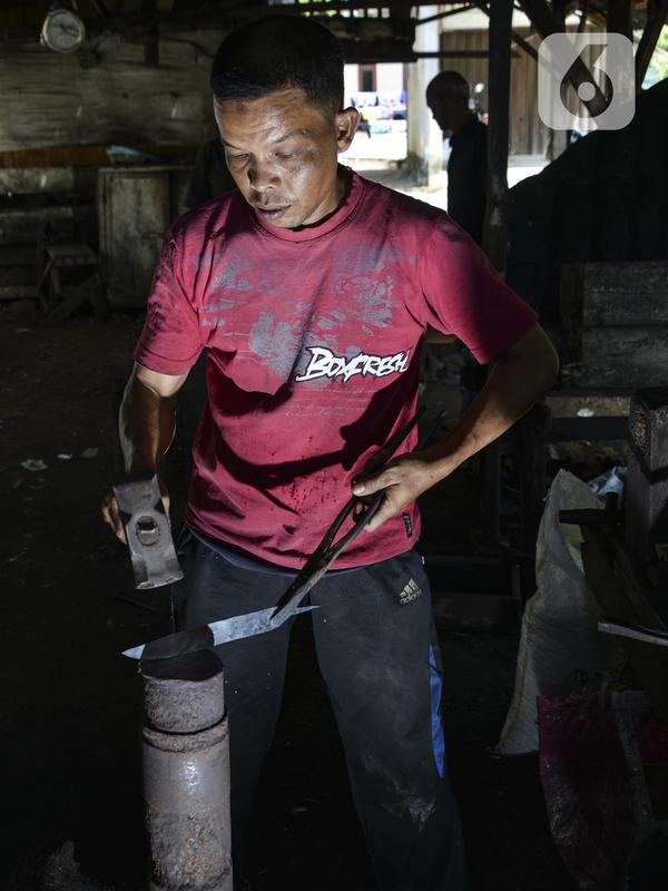 Seorang pandai mengetok baja untuk membuat pisau di bengkel tradisional di Darul Imarah, provinsi Aceh (4/11/2019). Lebih 70 persen warga di desa ini memiliki bekerja sebagai pengrajin pandai besi. (AFP Photo/Chaideer Mahyuddin)