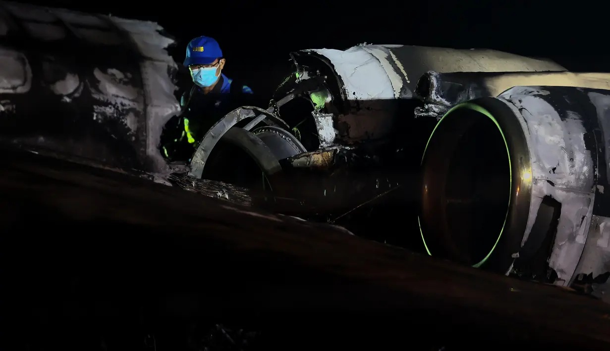 Petugas memeriksa puing-puing pesawat yang mengalami kecelakaan di ujung landasan pacu 24 di Bandara Internasional Ninoy Aquino, Manila, Filipina (29/3/2020).  Kecelakaan terjadi di area runway. Pesawat yang bertujuan ke Jepang itu dilaporkan terbakar ketika baru lepas landas. (Xinhua/Rouelle Umali)