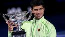 Carlos Alcaraz memamerkan piala usai berhasil menjuarai Australian Open 2026 setelah menaklukkan Novak Djokovic dalam laga sengit yang dilangsungkan di Melbourne Park pada (1/2/2026) sore WIB. (AFP/Izhan Khan)