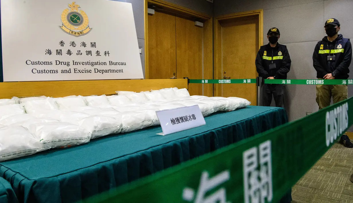 Petugas Bea Cukai berjaga dekat barang bukti berupa paket berisi kristal metamfetamin atau sabu selama konferensi pers di Hong Kong, Selasa (17/12/2019). Sekitar 110 kg kristal metamfetamin atau sabu disita pada 5 Desember lalu di bandara Internasional Hong Kong. (ANTHONY WALLACE / AFP)