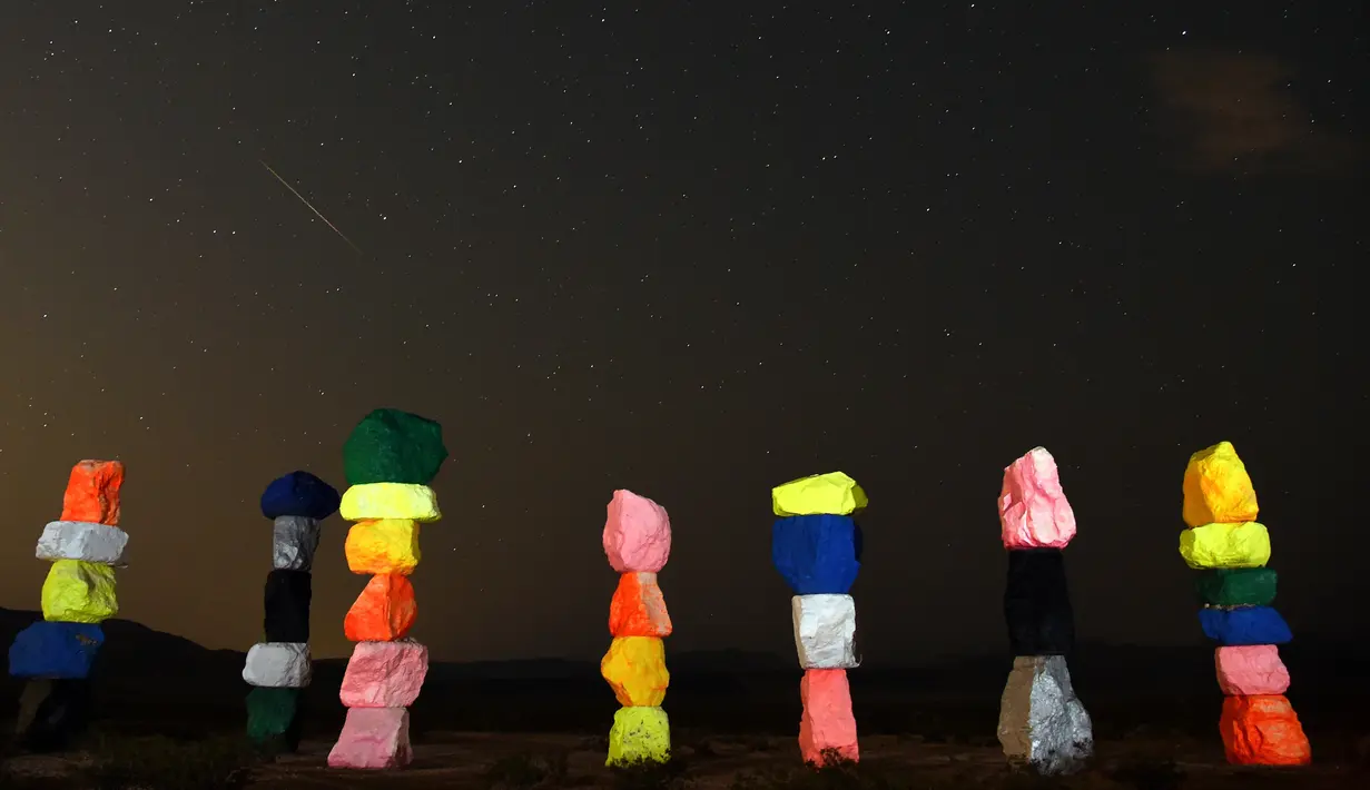 Meteor Perseid melintasi langit di atas instalasi seni "Seven Magic Mountains" dekat Jean, Nevada (13/8). Puncak hujan meteor perseid terjadi pada 11-12 Agustus dan 12-13 Agustus. (AFP Photo/Ethan Miller)