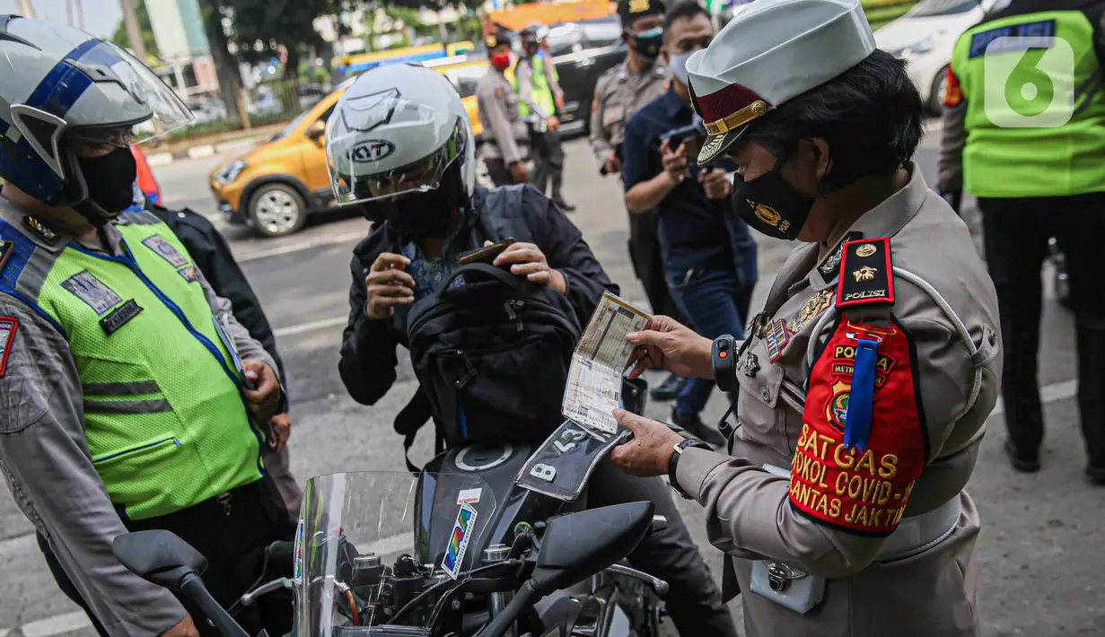 Petugas kepolisian lalu lintas mengecek STNK pengendara motor saat Operasi Zebra Jaya 2020 di kawasan Cawang, Jakarta, Senin (26/10/2020). Operasi Zebra Jaya dilaksanakan pada 26 Oktober-8 November 2020 untuk menekan jumlah pelanggaran lalu lintas. (Liputan6.com/Faizal Fanani)
