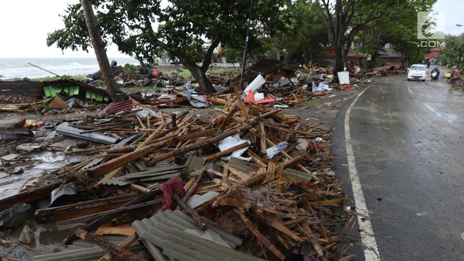 Kendaraan melintas di antara puing-puing setelah tsunami menerjang kawasan Anyer, Banten, Minggu (23/12). Tsunami menerjang pantai di Selat Sunda, khususnya di daerah Pandenglang, Lampung Selatan, dan Serang. (Liputan6.com/Angga Yuniar)