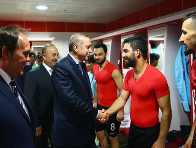 Presiden Turki, Tayyip Erdogan, masuk ke ruang ganti menyalami gelandang Timnas Turki, Arda Turan, jelang laga kualifikasi Piala Dunia melawan Finlandia di Stadion Antalya, Turki, Jumat (24/3/2017). Turki menang 2-0 atas Finlandia. (AFP/Kayhan Ozer)