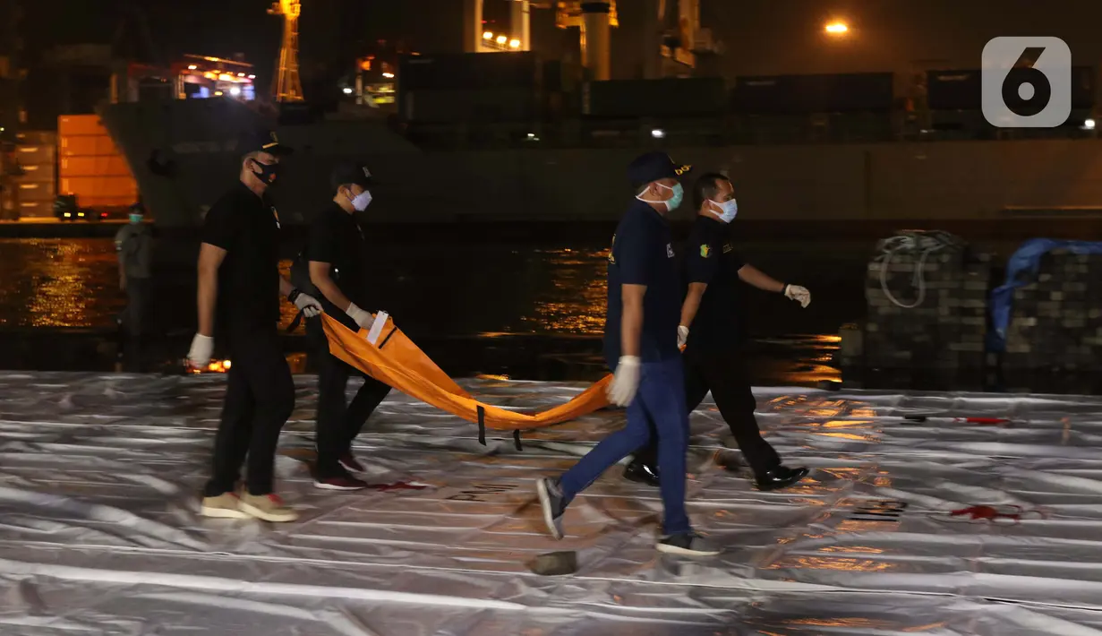 Tim DVI Polri membawa kantong jenazah yang diduga berisi bagian tubuh penumpang pesawat Sriwijaya Air SJ 182 di Dermaga JICT 2, Jakarta, Minggu (10/1/2021) dini hari. Sriwijaya Air SJ 182 hilang kontak dalam penerbangan dari Jakarta menuju Pontianak. (Liputan6.com/Helmi Fithriansyah)