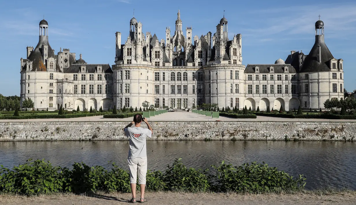 Seorang pengunjung mengambil gambar Kastil Chambord, di Chambord, Prancis pada 22 Juli 2020. Bangunan bersejarah ini merupakan salah satu kastil terbesar di Prancis sekaligus lokasi nyata yang menginspirasi film pertama Beauty and The Beast, 26 tahun lalu. (Photo by Ludovic MARIN / AFP)