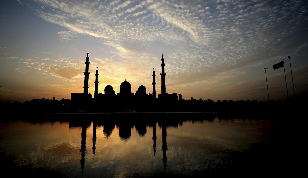 Matahari terbenam di belakang Masjid Agung Sheikh Zayed di Abu Dhabi, Uni Emirat Arab (8/11/2019). Masjid ini adalah masjid terbesar ketiga di dunia setelah masjid di Mekkah dan Madinnah. (AFP Photo/Kamran Jebreili)