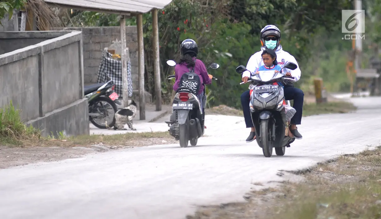 Pengendara sepeda motor mengenakan masker saat melintas di Desa Pempatan, Karangasem, Bali, Sabtu (30/6). Pascaerupsi Gunung Agung, abu vulkanik masih menyelimuti kawasan tersebut. (Merdeka.com/Arie Basuki)