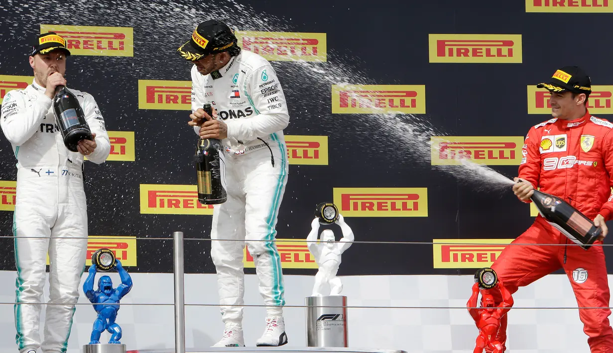 Pebalap Mercedes Lewis Hamilton (tengah) disemprot sampanye oleh pebalap Ferrari Charles Leclerc (kanan) disaksikan pebalap Mercedes Valtteri Bottas saat menjuarai F1 GP Prancis 2019 di Sirkuit Paul Ricard, Minggu (23/6/2019). (AP Photo/Claude Paris)