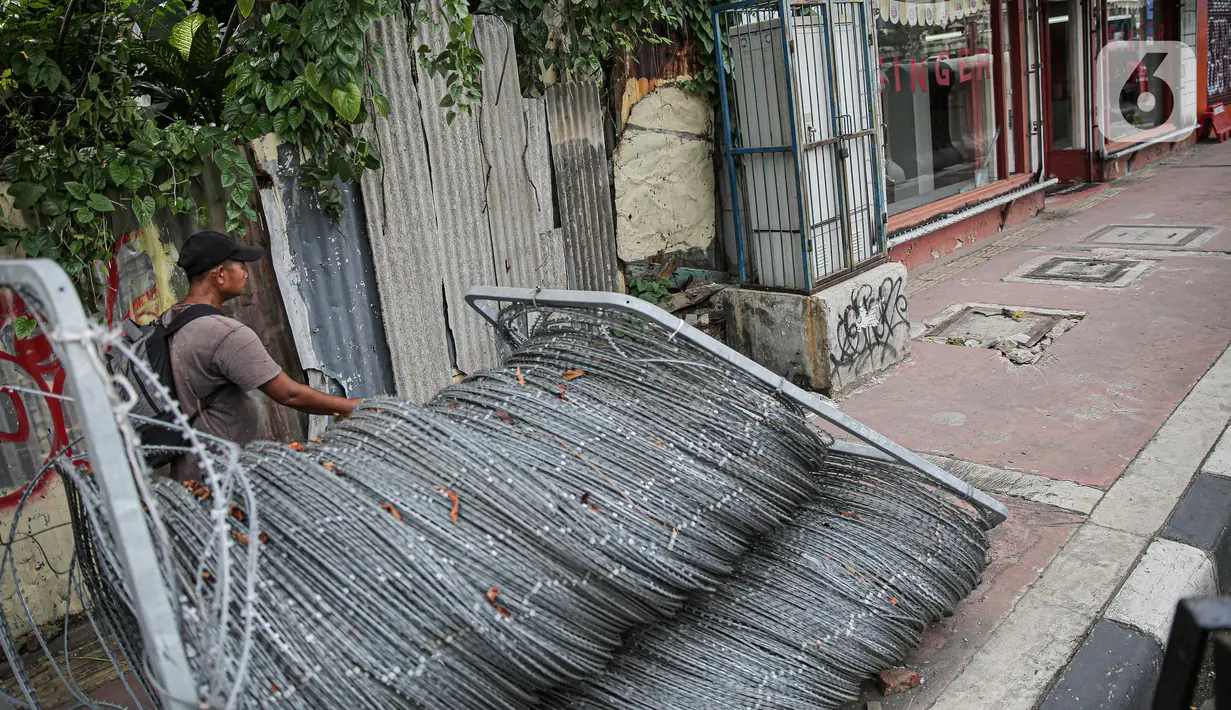 Warga berjalan kaki di samping barrier atau penghalang di kawasan Harmoni, Jakarta, Kamis (27/10/2022). Barrier yang biasa digunakan ketika terjadi demonstrasi Itu menyulitkan pejalan kaki saat melintas di trotoar. (Liputan6.com/Faizal Fanani)