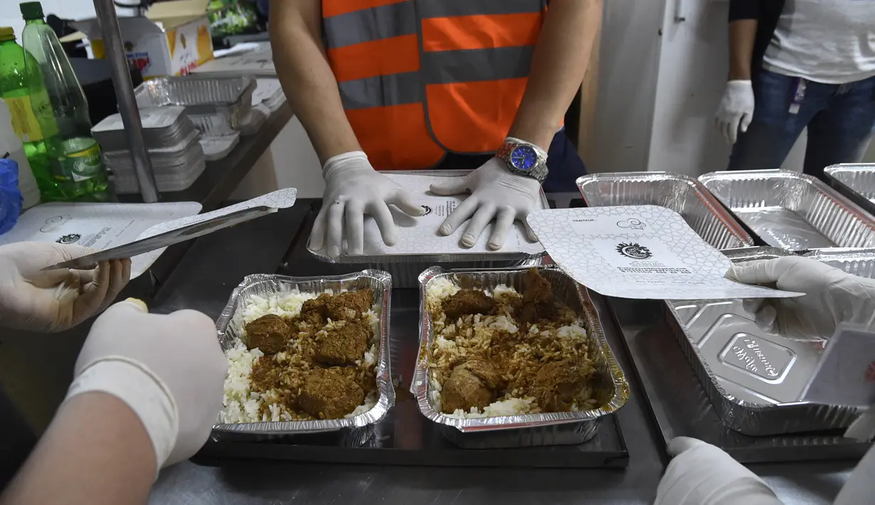 Relawan dari asosiasi Nass el-Khir mengemas kotak makanan sebelum didistribusikan kepada mereka yang membutuhkan selama bulan suci Ramadan di Aljir, Aljazair, Senin (18/5/2020). (RYAD KRAMDI/AFP)