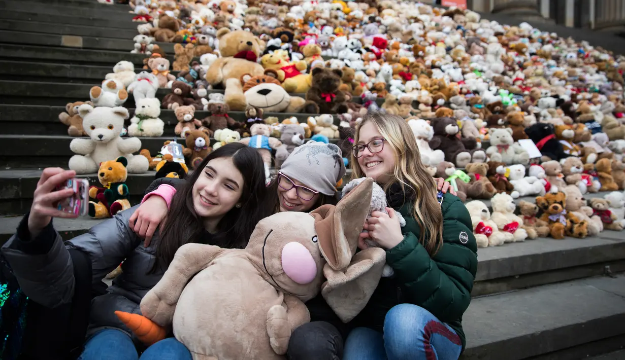 Siswa berswafoto sebelum meletakkan boneka beruang atau Teddy Bears di tangga Concert Hall, Berlin, Kamis (15/3). 740 boneka itu dipajang di tengah kegiatan Organisasi Visi Dunia yang memiliki tujuan misi kemanusiaan. (AFP PHOTO/Odd ANDERSEN)