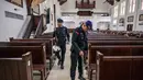 Menggunakan alat metal detektor, personel dari unit Gegana dan Jihandak Brimob Polda Jawa Timur melakukan penyisiran setiap area untuk memastikan keamanan guna kelancaran ibadah Natal. Tampak dalam foto, personel dari unit Gegana dan Jihandak Brimob Polda Jawa Timur melakukan pemeriksaan di dalam area Gereja Katedral Hati Kudus Yesus, atau yang dikenal secara lokal sebagai gereja "Hati Kudus Yesus", Surabaya, pada Rabu 24 Desember 2025. (JUNI KRISWANTO/AFP)
