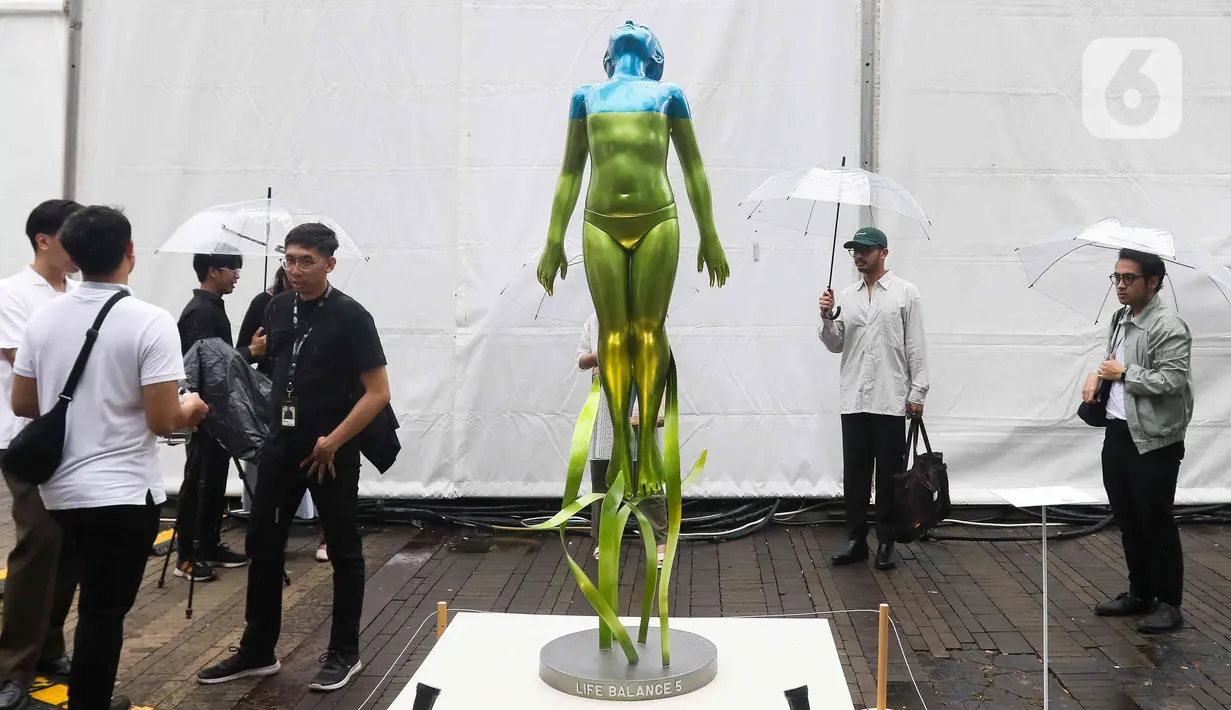 Pengunjung melihat karya seni yang ditampilkan dalam pameran Art Jakarta Gardens 2023 di Hutan Kota Plataran, Senayan, Jakarta Pusat, Selasa (7/2/2023). Pameran seni Art Jakarta Gardens kembali digelar tahun ini mulai dari tanggal 7 - 12 Februari 2023, dalam pameran ini, pengunjung dapat menjelajahi kombinasi presentasi karya seni rupa yang ditampilkan dari dalam dan luar ruangan dengan karya berupa patung, instalasi, dan objek dua dimensi. (Liputan6.com/Herman Zakharia)