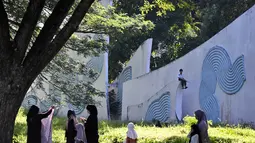 Momen ini menjadi refleksi untuk menyatukan kenangan pahit masa lalu dengan kepedihan akibat bencana alam terkini. Tampak dalam foto, seorang anak duduk di monumen peringatan sementara orang-orang berdoa untuk kerabat yang kehilangan nyawa dalam peristiwa gempa dan tsunami Aceh pada 2004 lalu di sebuah kuburan massal di Siron, pada 26 Desember 2025. (CHAIDEER MAHYUDDIN/AFP)