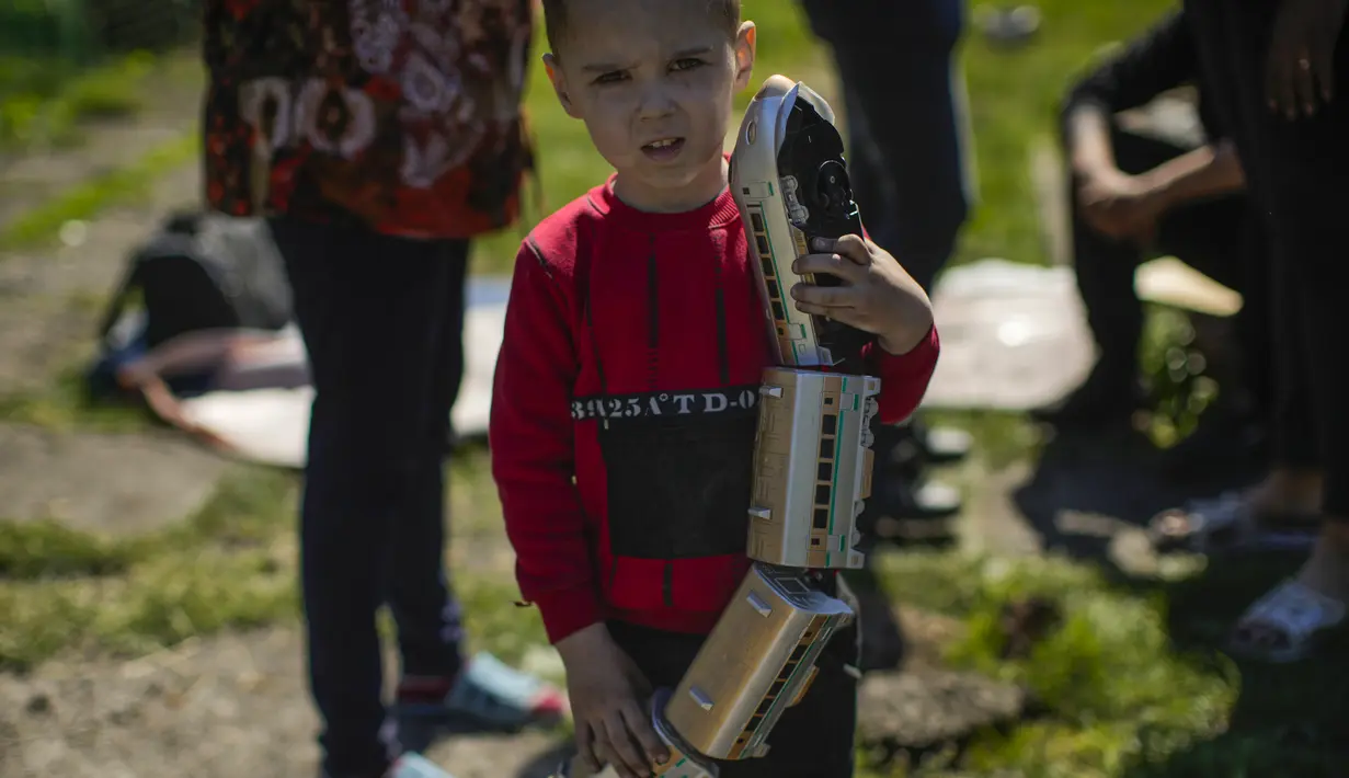 Seorang anak memegang kereta mainan di luar rumah keluarganya yang rusak parah setelah serangan Rusia di Pokrovsk, Ukraina timur, Rabu (25/5/2022). Dua roket menghantam kota Pokrovsk, di wilayah Donetsk pada Rabu pagi, menyebabkan sedikitnya empat cedera. (AP Photo/Francisco Seco)