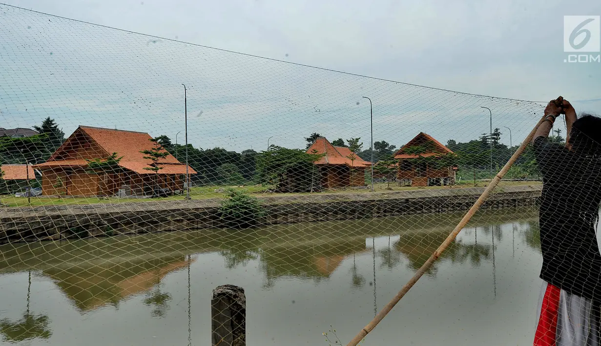 Seorang pria membenarkan jaring dekat rumah Betawi yang berada di Setu Babakan, Jagakarsa, Jakarta Selatan, Minggu (10/3). Rumah Betawi yang dibangun di atas pulau buatan itu akan menceritakan keseharian orang Betawi. (merdeka.com/Arie Basuki)