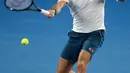 Petenis Swiss, Roger Federer mengembalikan bola ke arah Taylor Fritz dari AS dalam babak 32 besar Australia Terbuka di Melbourne, Jumat (18/1). Federer melaju mulus ke babak 16 besar setelah menang tiga set langsung 6-2 7-5 6-2. (AP/Kin Cheung)