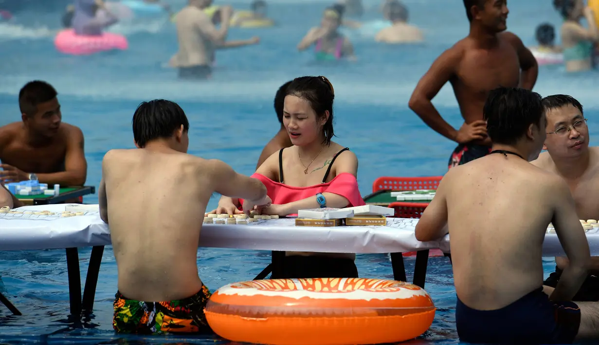 Sejumlah orang bermain catur di dalam kolam renang saat cuaca panas melanda wilayah Chongqing di Tiongkok, Rabu (2/8). Tiongkok saat ini dilaporkan sedang mengalami cuaca panas dengan suhu di beberapa daerah hampir mencapai 40 derajat celcius. (STR / AFP)