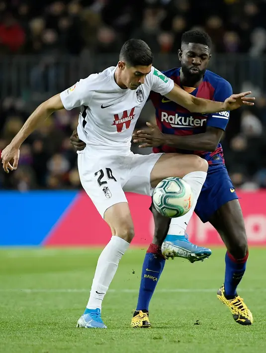 Pemain Granada, Carlos Fernandez berebut bola dengan bek Barcelona, Samuel Umtiti pada lanjutan pertandingan La Liga Spanyol di Camp Nou, Minggu (19/1/2020). Barcelona sukses meraih kemenangan atas tamunya Granada dengan skor tipis 1-0. (LLUIS GENE / AFP)