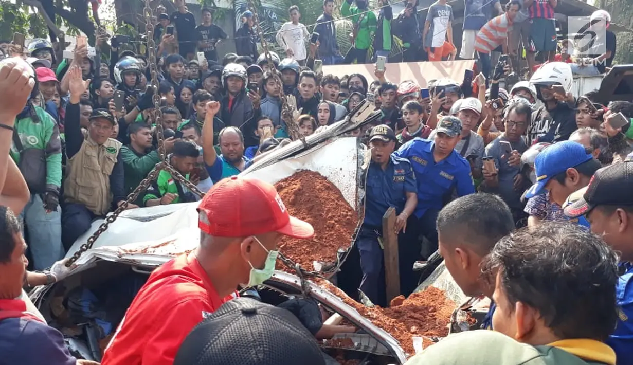 Warga berkerumun menyaksikan proses evakuasi bangkai mobil kecelakaan maut yang hancur tertindih badan truk muatan tanah di Karawaci, Tangerang, Kamis (1/8/2019). Sopir truk yang menimpa mobil dan menewaskan 4 orang itu kabur setelah kecelakaan maut terjadi. (Liputan6.com/Pramita Tristiawati)