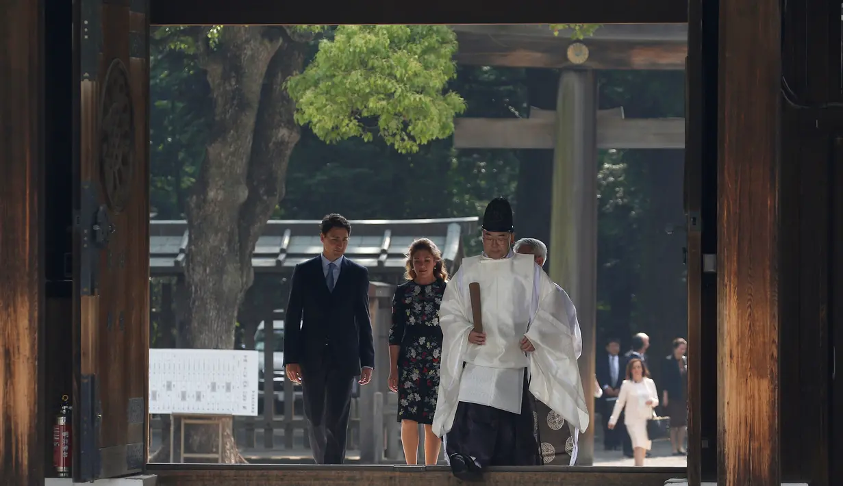 PM Kanada Justin Trudeau  dan istri berjalan dipimpin oleh Shinto Imam As saat mengunjungi Kuil Meiji di Tokyo, Jepang (24/5). Kedatangan Justin Trudeau untuk melakukan pertemuan KTT G7 Ise-Shima. (REUTERS /Issei Kato)