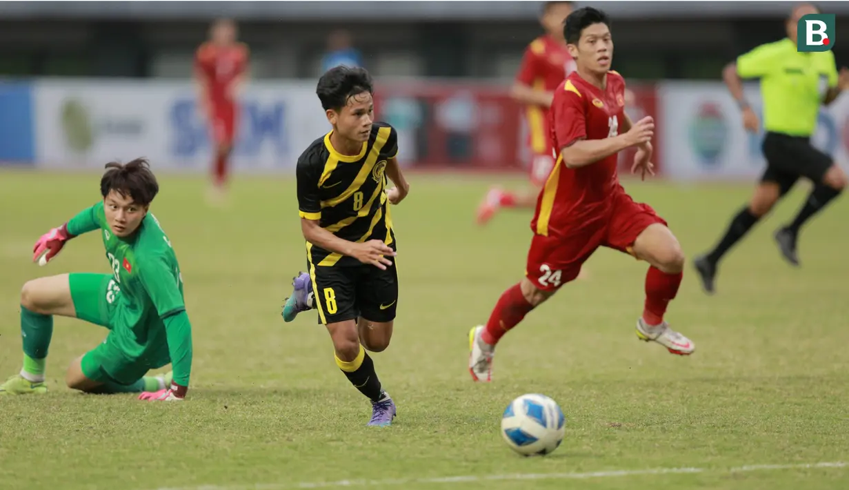 Pemain Malaysia U-19, Haikal Danis (tengah) melewati kiper Vietnam U-19, Cao Van Binh pada laga semifinal Piala AFF U-19 2022 di Stadion Patriot Candrabhaga, Bekasi, Rabu (13/7/2022). (Bola.com/M Iqbal Ichsan)