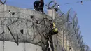 Seorang pria Palestina memanjat pagar perbatasan yang memisahkan Tepi Barat dengan Yerusalem di Distrik Beit Hanina, Yerusalem, Senin (7/10/2019). Banyak warga Palestina dari Tepi Barat menyeberang secara ilegal ke Israel setiap hari untuk mencari pekerjaan. (AHMAD GHARABLI/AFP)