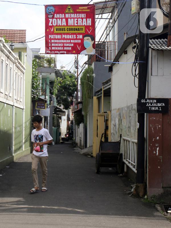 Warga melintasi spanduk zona merah kawasan RW 01 Kelurahan kalibata, Jakarta, Selasa (9/2/2021). Pemerintah mulai menerapkan PPKM skala mikro mulai 9-22 Februari 2021 untuk 7 provinsi yakni DKI Jakarta, Jawa Barat, Banten, Jawa Tengah, Yogyakarta, Jawa Timur, dan Bali. (Liputan6.com/Herman Zakharia)