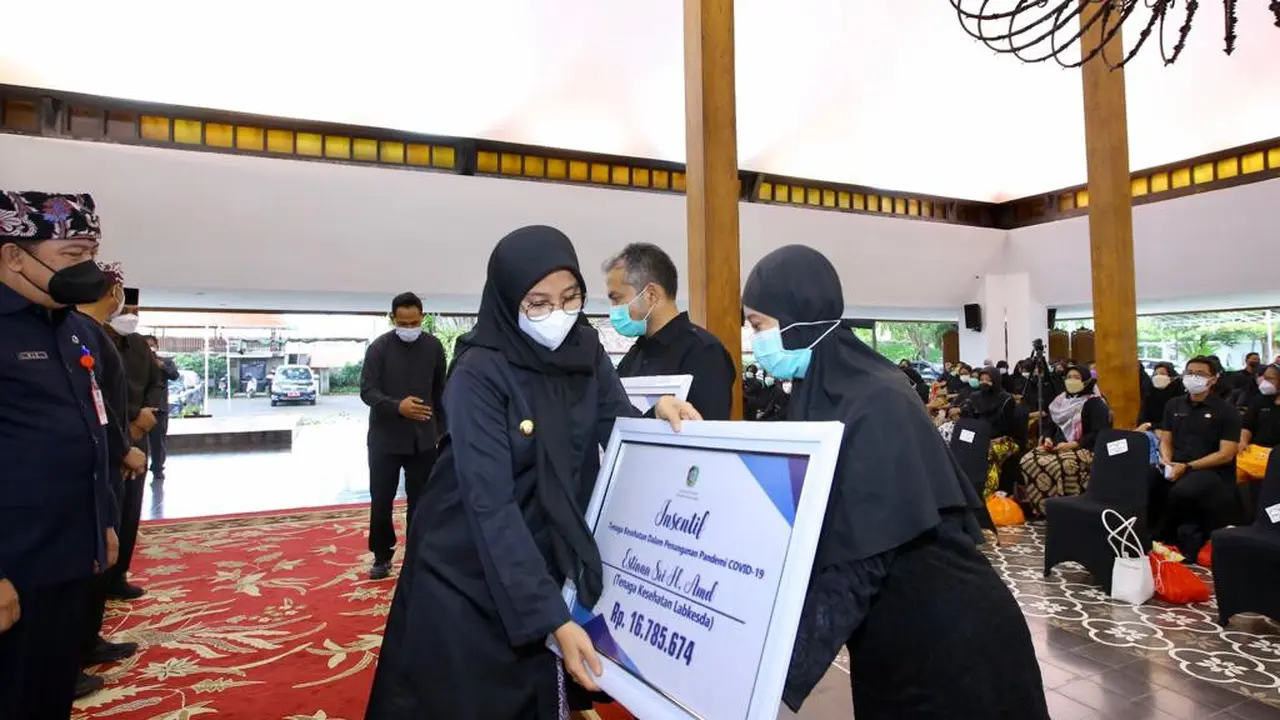Bupati Banyuwangi Ipuk Fiestiandani menyerahkan insentif ke nakes. (Dian Kurniawan/Liputan6.com)