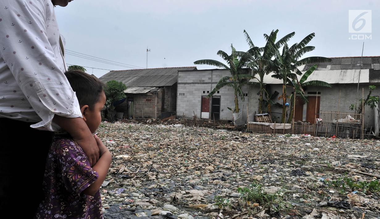 Warga bersama anaknya melihat sampah yang memenuhi Kali Pisang Batu, Bekasi, Jawa Barat, Rabu (9/1). Warga tetap beraktivitas sehari-hari meski bau tak sedap menghantui mereka akibat tumpukan sampah di Kali Pisang Batu. (Merdeka.com/Iqbal S. Nugroho)