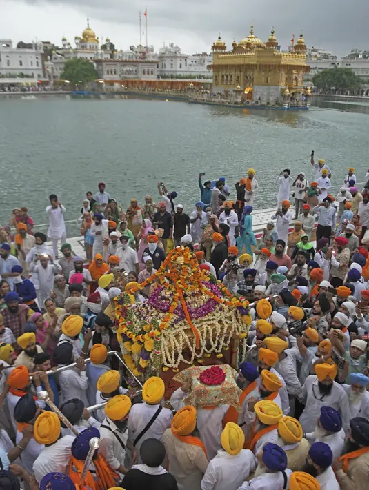 Kepala pendeta Sikh Jagtar Singh (tengah) membawa teks pokok agama Sikhisme, Guru Granth Sahib selama prosesi keagamaan dari Gurudwara Ramsar ke Akal Takht Sahib di Kuil Emas, Amritsar, India, Rabu (19/8/2020). Acara ini untuk memperingati 416 tahun pelantikan Guru Granth Sahib. (NARINDER NANU/AFP)