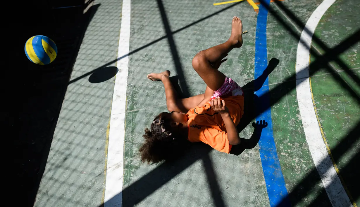 Seorang anak sedang asik bermain bola voli pada program Volleyball Development Training yang digagas oleh FIVB di Formiga favela, Rio de Janeiro, (2/8/2016). (AFP/Leon Neal)