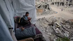 Namun, asa untuk berjuang, bertahan, dan melanjutkan kehidupan terus membara. Tampak dalam foto, Omar Qutay duduk di atas tempat tidur yang diletakkan di balkon rumahnya yang sebagian hancur di lingkungan Al-Karama, Kota Gaza, Rabu, 24 November 2025. (AP Photo/Jehad Alshrafi)