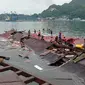 Orang-orang berdiri pada atap toko yang runtuh di pelabuhan setelah gempa magnitudo 5,1 di Jayapura, Provinsi Papua, Indonesia, 9 Februari 2023. Korban meninggal dalam gempa Jayapura adalah Rista (25), Ani (26), Astrid (25), dan Maya (27). (FAISAL NARWAWAN/AFP)