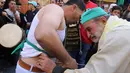 Warga muslim Sufi menusukkan benda tajam ke perut salah satu peserta saat perayaan Maulid Nabi Muhammad SAW di Sidon, Lebanon (30/11). Tradisi yang mirip debus ini selalu digelar setiap tahunnya. (AFP Photo/Mahmoud Zayyat)