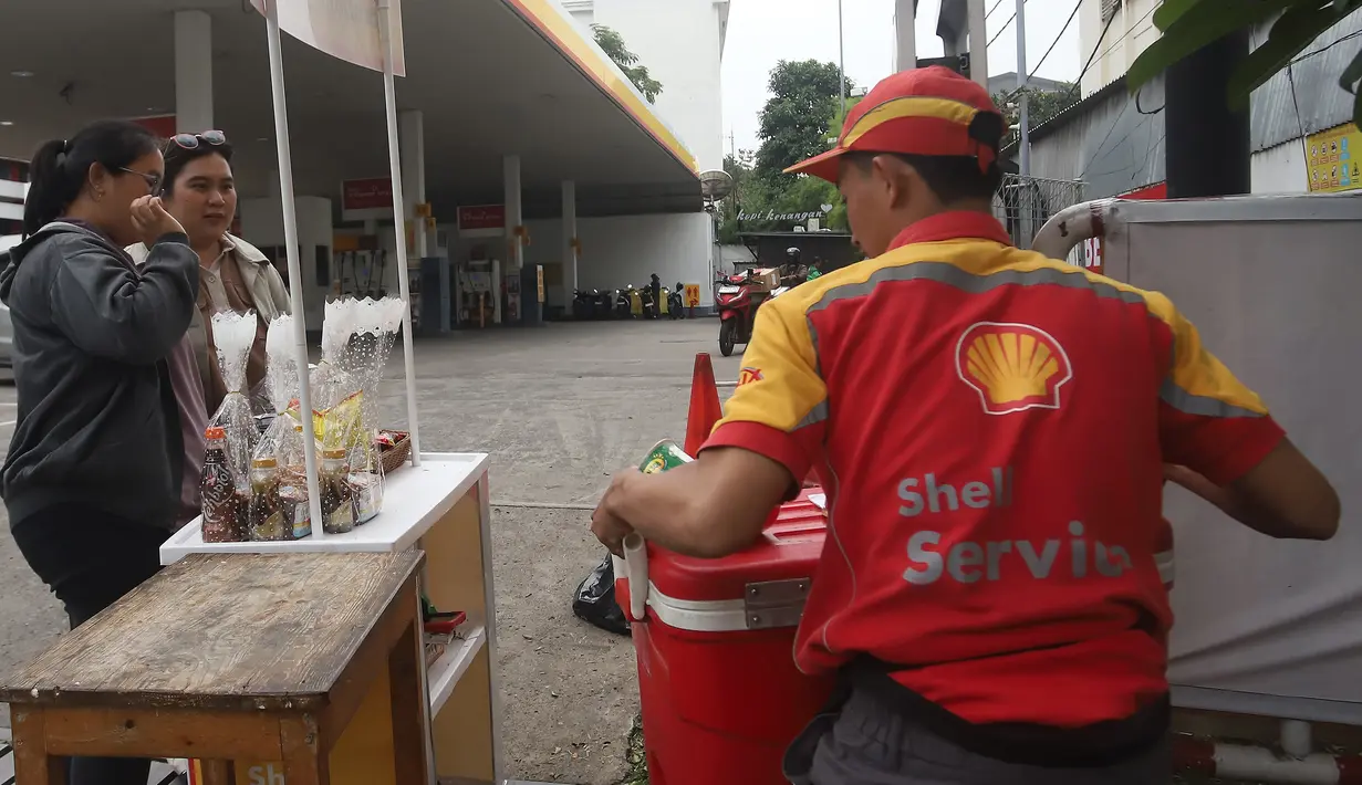 Warga membeli minuman dingin yang dijajakan karyawan atau petugas Stasiun Pengisian Bahan Bakar Umum (SPBU) di depan SPBU Shell, Jalan Gunung Sahari, Jakarta, Kamis (18/9/2025). (merdeka.com/Arie Basuki)