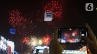 Pengunjung mengambil gambar pesta kembang api di langit saat Jakarta Fair ke-53 atau Pekan Raya Jakarta (PRJ) di JiExpo Kemayoran, Jakarta Pusat, Selasa (21/6/2022) malam. Pesta kembang api menggelegar di kawasan PRJ bertepatan dengan HUT Jakarta yang jatuh pada besok, 22 Juni 2022. (Liputan6.com/Herman Zakharia)