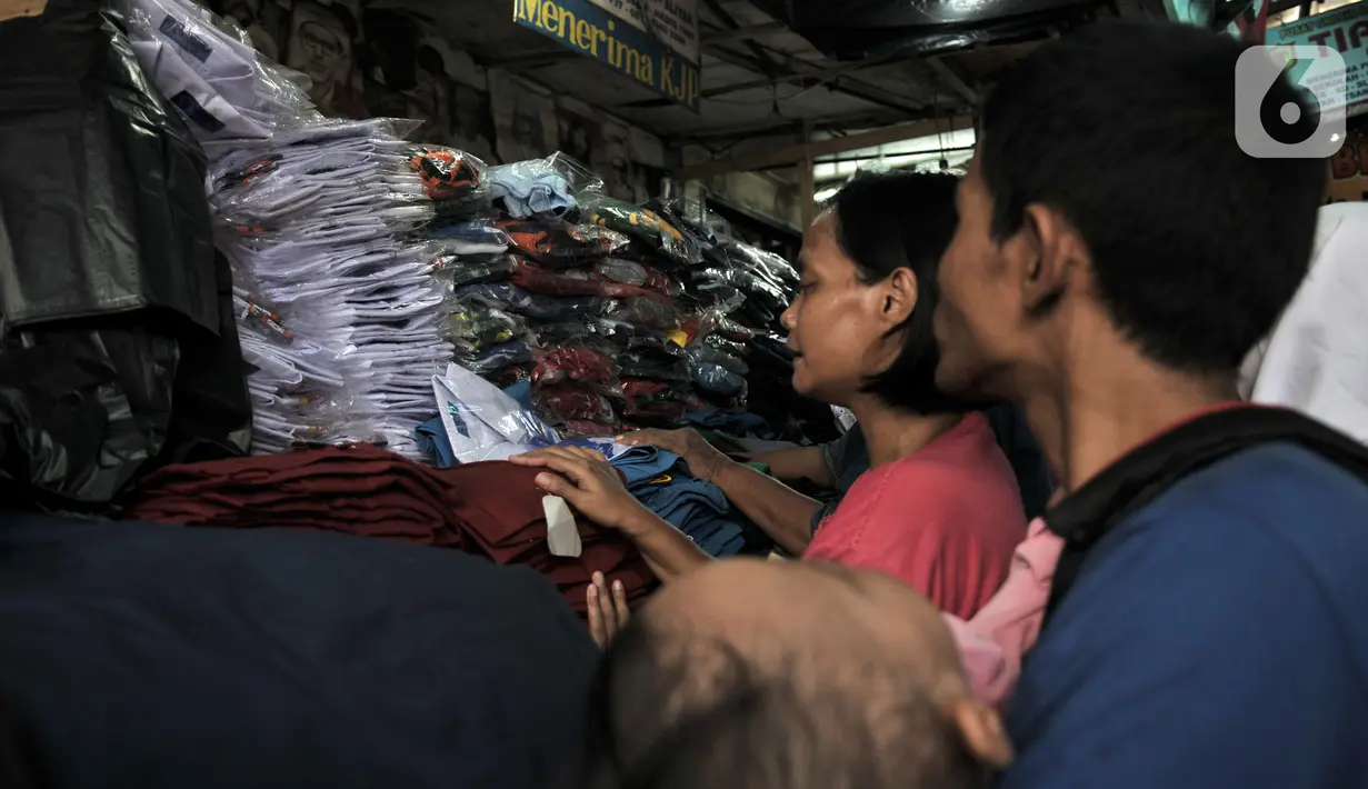 Pembeli memilih seragam sekolah di Pasar Jatinegara, Jakarta, Minggu (5/1/2020). Jelang hari pertama belajar di semester baru, warga terdampak banjir di Kampung Melayu dan sekitarnya terpaksa membeli seragam baru untuk anaknya akibat banjir yang merendam rumah mereka. (merdeka.com/Iqbal Nugroho)