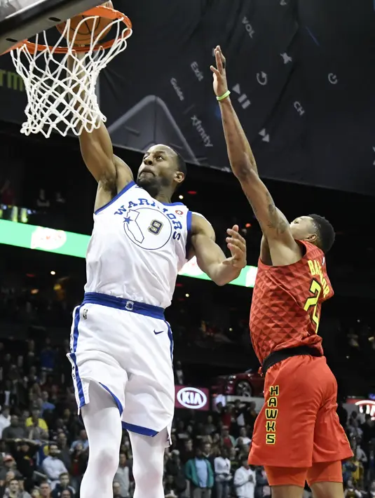 Pemain Warriors, Andre Iguodala #9 melakukan dunk saat diadang pemain Atlanta Hawks, Kent Bazemore pada laga NBA basketball game  di Philips Arena, Atlanta, (2/3/2018). Warriors menang 114-109. (AP/John Amis)
