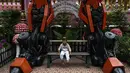 Seorang anak berpose di bawah patung logam 'Transformers' di kuil Buddha Wat Tha Kien di Nonthaburi, Thailand (18/6). Kuil ini tengah berjuang untuk tetap relevan di era modern dengan meletakkan patung logam Transformers. (AFP Photo/Lillian Suwanrumpha)