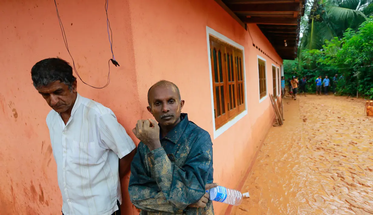 Warga menyaksikan evakuasi korban longsor di desa Bellana di distrik Kalutara, Sri Lanka, (26/5). Menteri Dalam Negeri Vajira Abeywardana mengatakan sekitar puluhan orang tewas dan hilang akibat musibah ini. (AP Photo / Eranga Jayawardena)