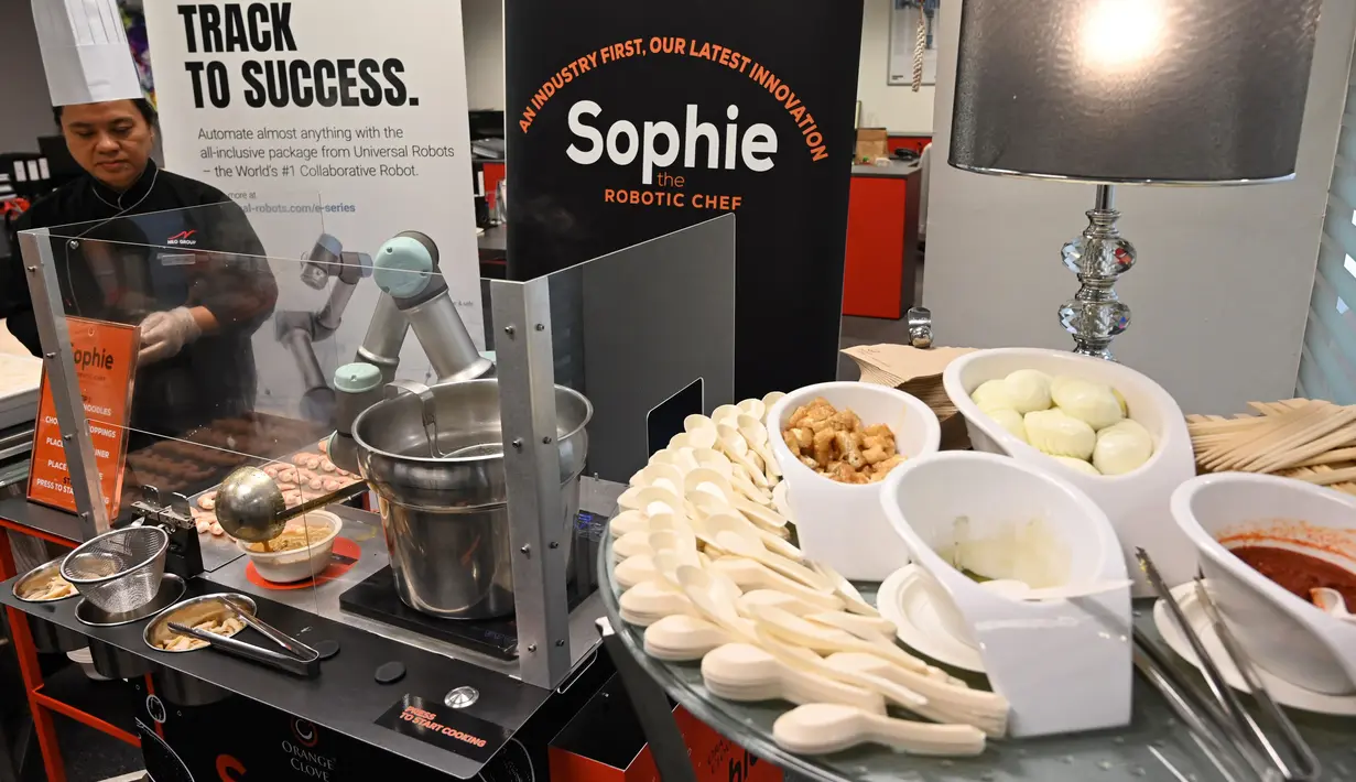Robot koki bernama Sophie meracik semangkuk laksa saat demonstrasi memasak di Singapura pada 26 Juli 2019. Inovasi robot penyaji makanan ini bakal semakin populer dan menjadi stasiun masak otomatis yang umum dipakai di Singapura.  (Roslan RAHMAN / AFP)