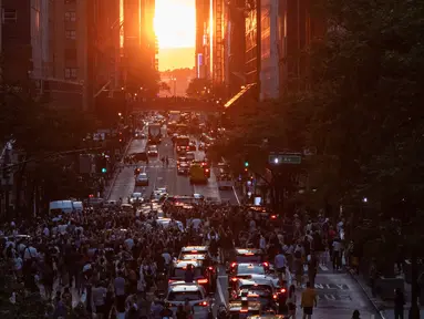 Matahari terbenam di Manhattan ketika fenomena "Manhattanhenge" di 42nd street, New York, Senin (11/7/2022). Manhattanhenge adalah keadaan dimana matahari terbenam tepat berada dalam garis lurus dengan jalanan Manhattan yang melintang dari timur ke barat. (Yuki IWAMURA / AFP)