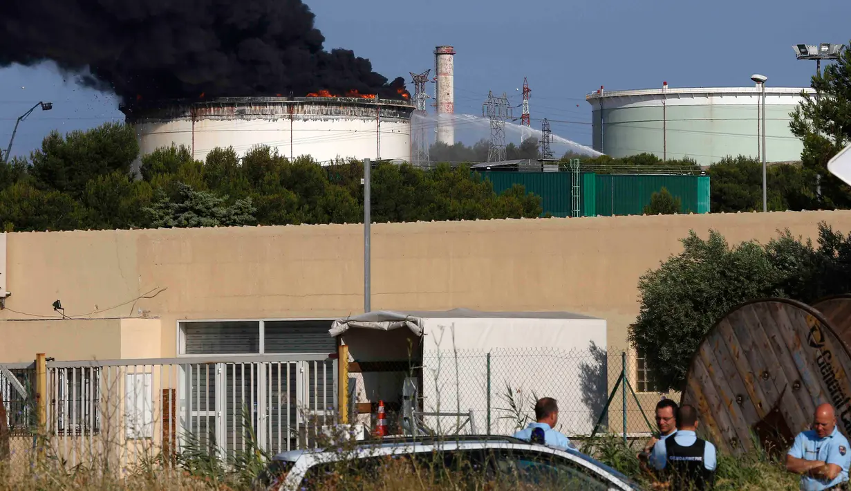 Sejumlah petugas berjaga di dekat kilang minyak milik perusahaan Amerika di Etang de Berre, Marseille, Perancis, (14/7/2015). kebakaran yang terjadi merupakan kebakaran terbesar kelima di Perancis. (REUTERS/Philippe Laurenson)