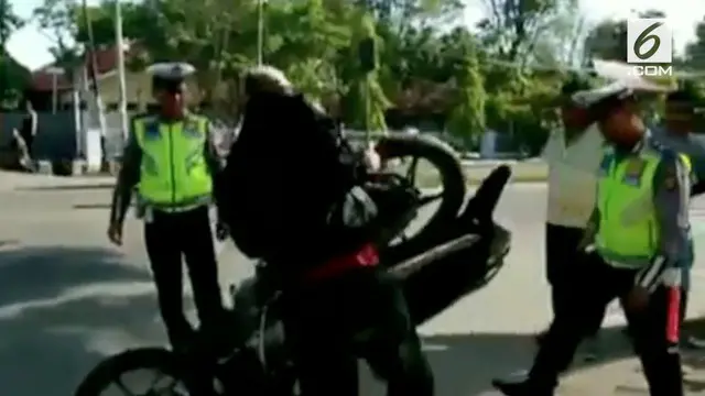 Tak terima ditilang oleh polisi, seorang pengendara membanting motornya sendiri di hadapan petugas.