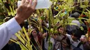 Daun palem digunakan sebagai simbol kemenangan dan damai. Tampak dalam foto, seorang pekerja gereja memercikkan air suci ke daun palem para umat selama upacara pemberkatan di luar Katedral Antipolo, kota Antipolo, provinsi Rizal, Filipina, saat memperingati Minggu Palma, 29 Maret 2026. (AP Photo/Aaron Favila)