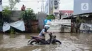 Pengendara motor mendorong kendaraannya yang mogok akibat memaksa menerobos banjir yang menggenangi Jalan KH Hasyim Ashari, Kota Tangerang, Banten, Selasa (4/3/2025). (Liputan6.com/Angga Yuniar)